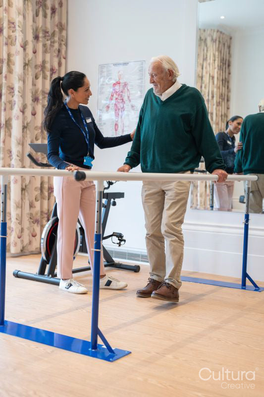 Female therapist assisting senior man walking on bars in exercise room