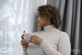 Woman with coffee cup looking through window