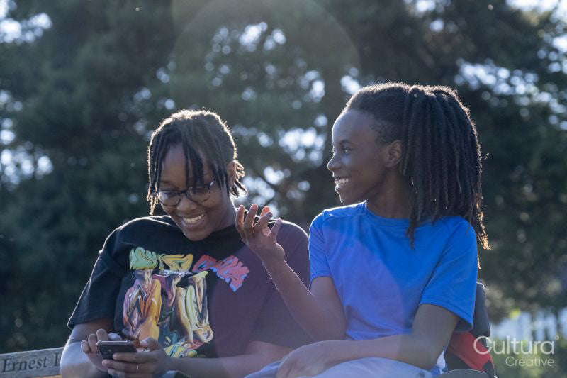 Teenage girl in wheelchair with friend relaxing in park
