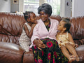 Great grandmother sitting on sofa with great granddaughters