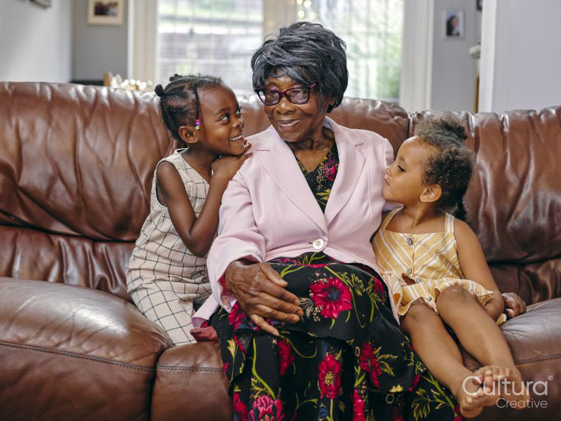 Great grandmother sitting on sofa with great granddaughters