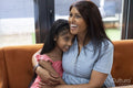 Smiling mother embracing daughter at home