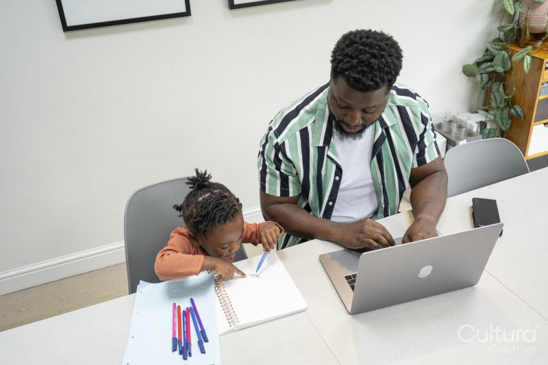 Father using laptop and daughter drawing in notepad