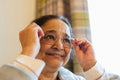Senior lady putting on eyeglasses at nursing home