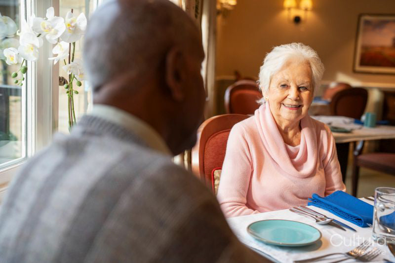Senior woman and man talking at table during meal in nursing home