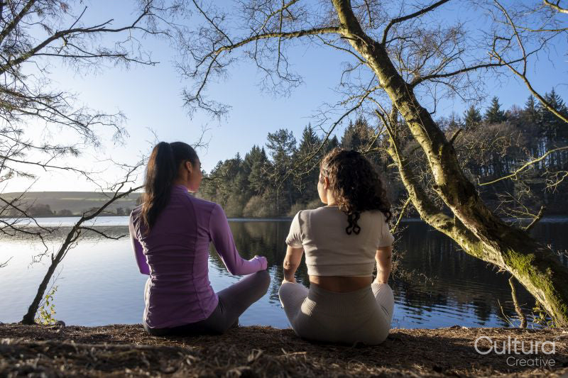 Young women meditating at lake