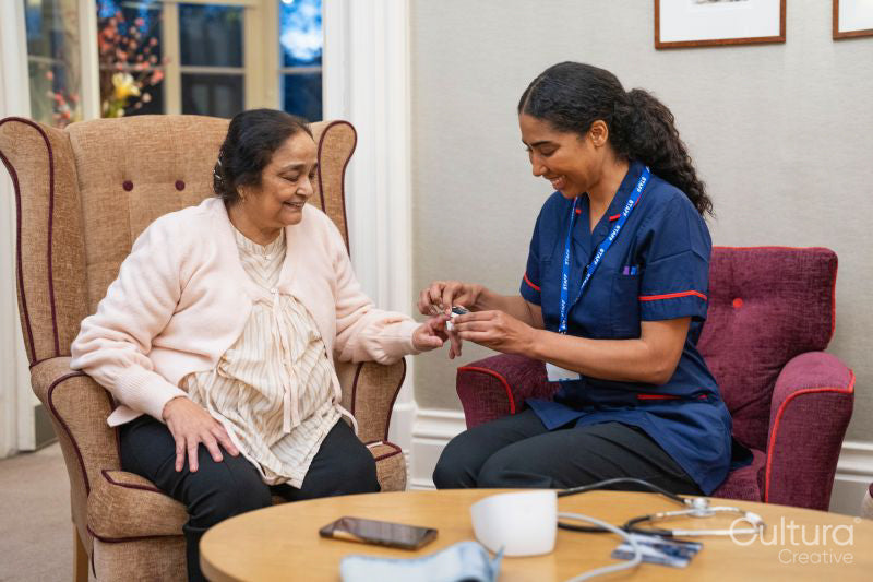 Nursing assistant using pulse oximeter on senior woman at nursing home