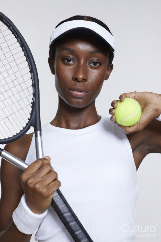 Studio portrait of athletic woman with tennis racket and ball