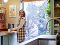 Smiling woman standing with tea cups in kitchen