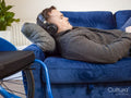 Man with headphones lying on sofa next to wheelchair