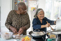 Two senior women preparing meal in kitchen