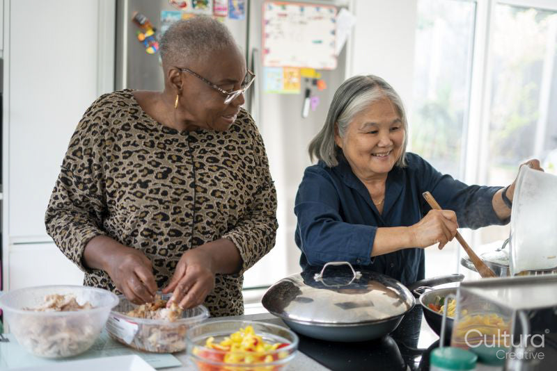 Two senior women preparing meal in kitchen