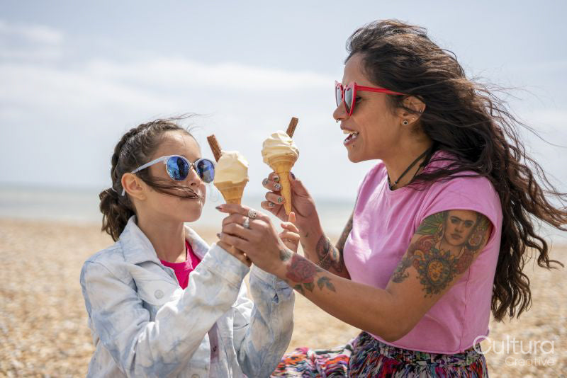 Mother and daughter eating ice cream on beach