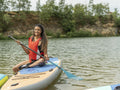 Smiling woman sitting on paddleboard on lake