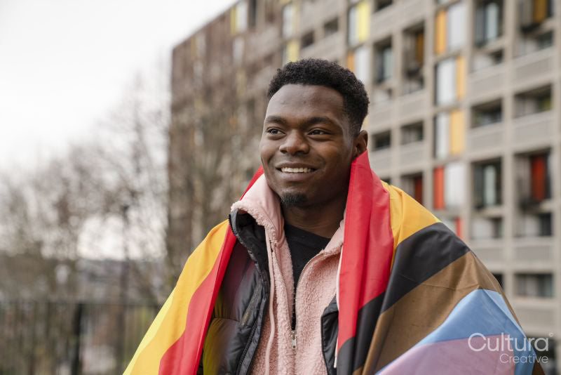 Smiling young man wrapped in progress pride flag