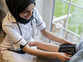 Female doctor adjusting blood pressure gauge on patients arm