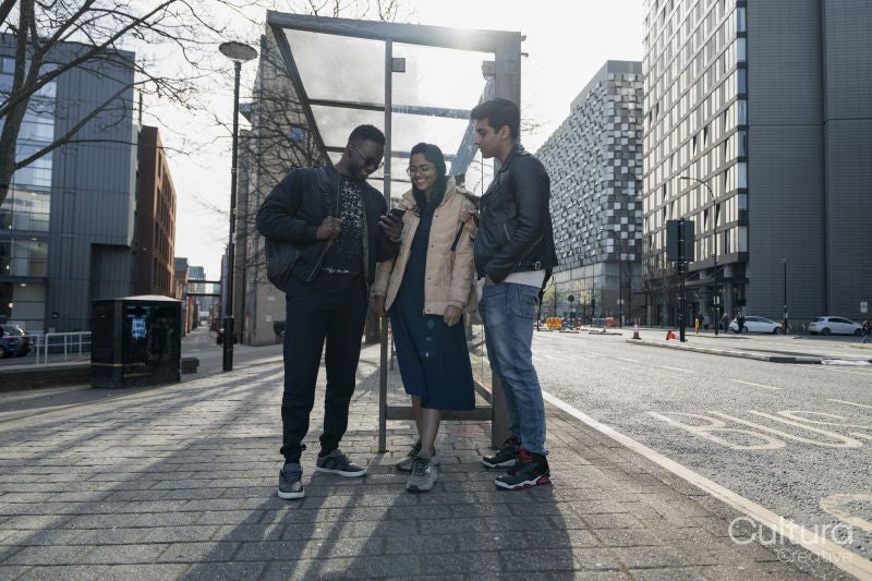 Smiling friends using phone on campus