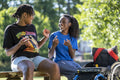 Teenage girl in wheelchair with friend in park