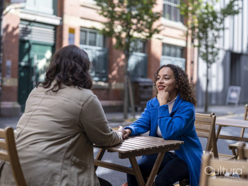 Smiling couple holding hands at sidewalk cafe table