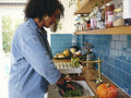Woman washing vegetables in kitchen sink
