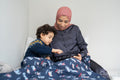 Mother and son using digital tablet in bed