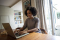 Smiling woman using laptop at home