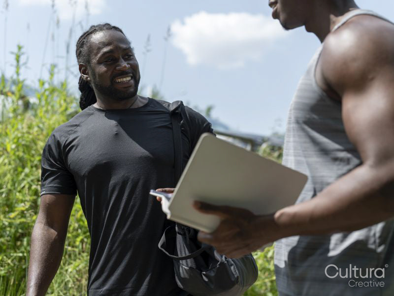 Two men planning workout on digital tablet