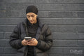 Young woman leaning on wall and using smartphone