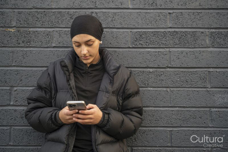 Young woman leaning on wall and using smartphone
