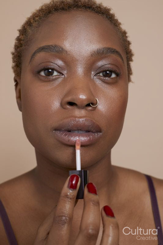 Studio portrait of woman applying lip gloss