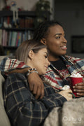 Two young women sitting on sofa drinking coffee with marshmallows