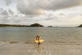 Indonesia, Lombok, Side view of surfers walking in sea at sunset