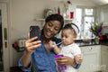 Woman using phone and taking care of baby daughter
