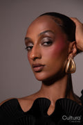 Woman in a black dress with gold earrings on a grey background