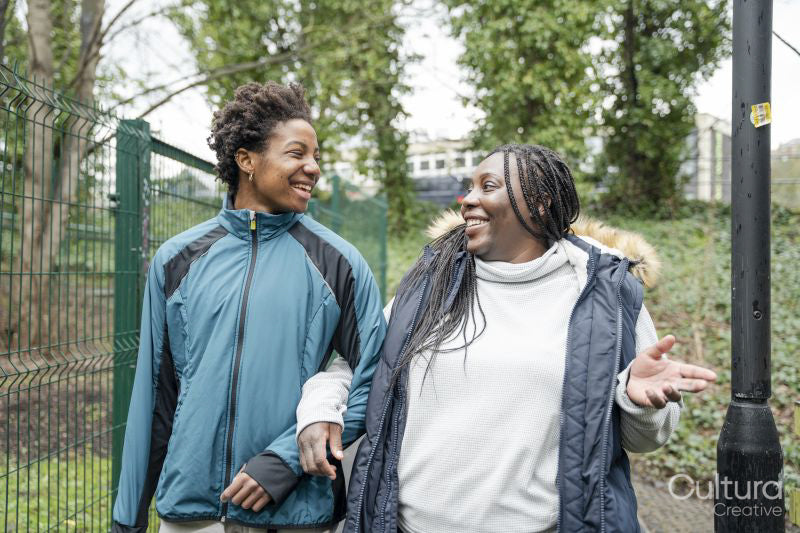 Mother and daughter talking while walking in park