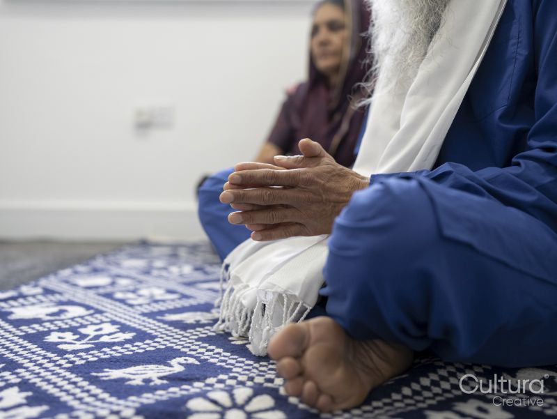 Senior couple in traditional clothing praying at home