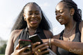 Smiling female friends using smart phones
