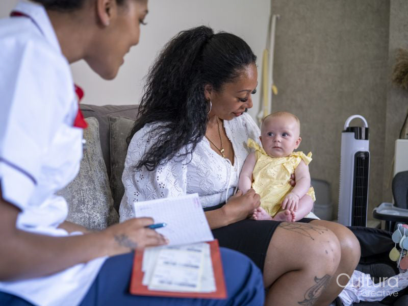 Nurse visiting woman with baby girl at their home