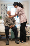 Nurse helping senior man to get dressed at nursing home
