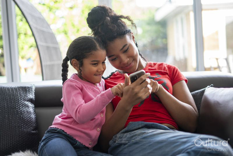 Two girls sitting on sofa looking at smartphone