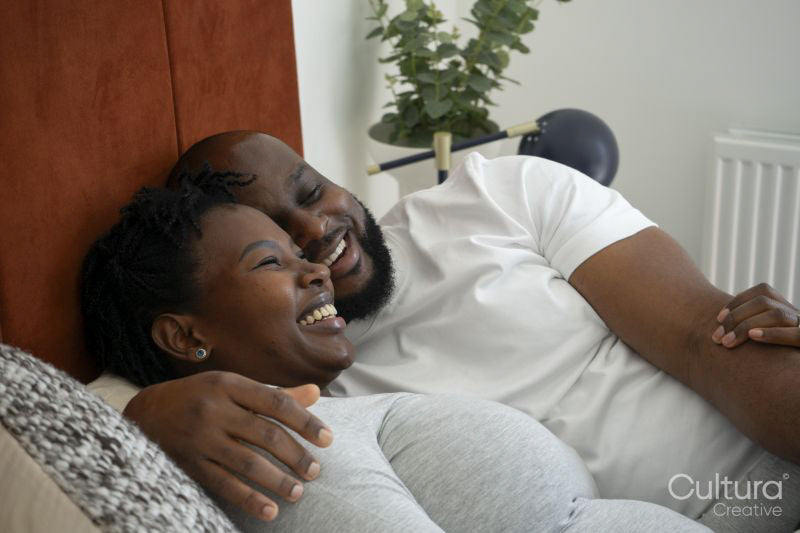 Smiling man embracing pregnant woman on bed