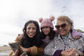 Grandmother, mother and daughter looking at smart phone on beach