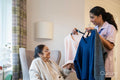 Nurse helping senior lady to choose clothes at nursing home