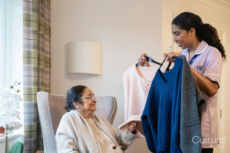 Nurse helping senior lady to choose clothes at nursing home