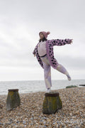 Girl standing on one leg on groyne with arms outstretched