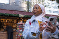 Young female tourist in hijab using phone in Christmas market