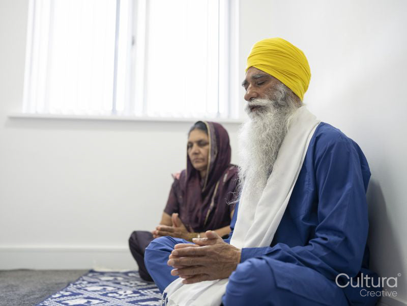 Senior couple in traditional clothing praying at home