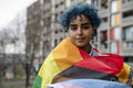 Portrait of young woman wrapped in progress pride flag