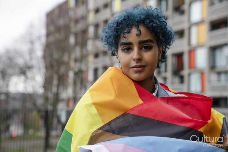 Portrait of young woman wrapped in progress pride flag