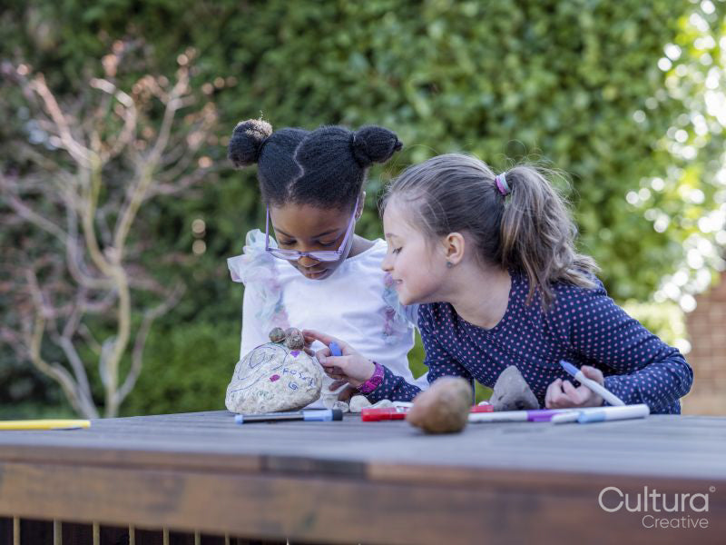 Girl friends painting rocks in back yard